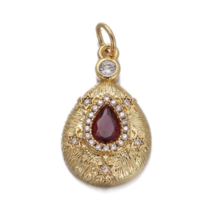 Macro detail of gold teardrop pendant with red pear-cut stone and zircon halo