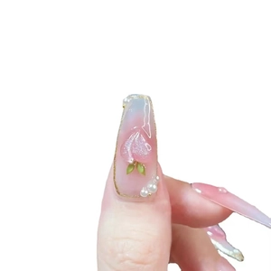 Detailed close-up of 3D peach nail art with white pearls and gold line accents