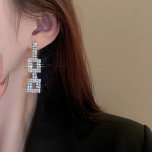 Close-up of a silver square earring with crystals on a model for a luxury look