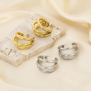 Close-up of gold and silver triple-layered C-shaped hoop earrings on stone display