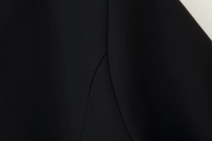 Close-up of black fabric texture and professional seam stitching on a fitted dress