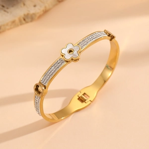 Détail d'un bracelet doré orné d'une fleur en nacre blanche et de zircons brillants