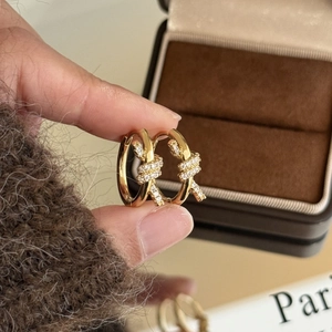 Gros plan de boucles d'oreilles nœuds dorées avec zircons blancs sur boîte vintage