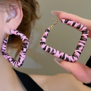 Gros plan de boucles d'oreilles créoles carrées imprimé léopard rose et cadre vintage