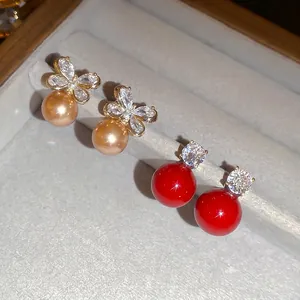 Bowknot pearl earrings and red zircon studs displayed on a grey velvet jewelry tray