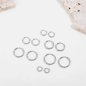 Macro view of silver hoop earrings in various sizes arranged on a stone background