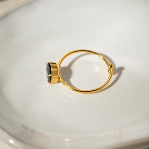 Detail of 18k gold plated ring featuring a black round zircon on a ceramic tray