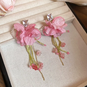 Detailed shot of pink fabric flower tassel earrings with green seed beads and zircons