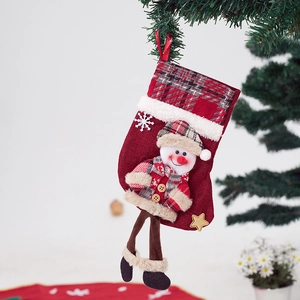 Detail of red burlap Christmas stocking with plush snowman decoration on tree branch