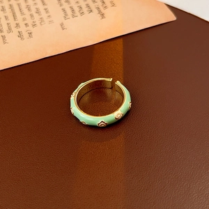 Macro di un anello vintage dorato con smalto verde menta e motivi a margherite bianche
