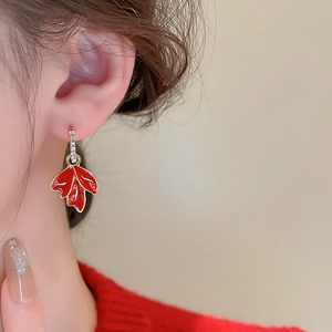 Gros plan de boucles d'oreilles feuille d'érable en émail rouge portées par un mannequin
