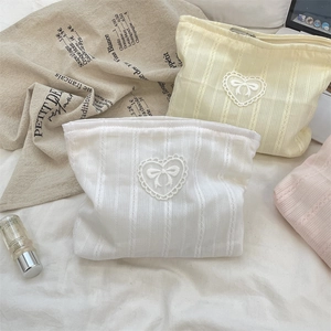 Macro view of macaron knitted bow makeup bags with lace heart details and zipper