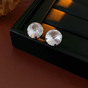 Macro close-up of sparkling round diamond stud earrings on brown leather and black box