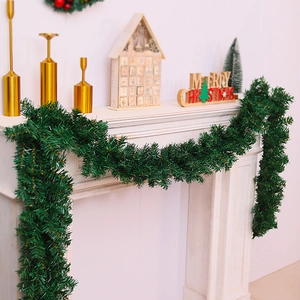 Detailed view of dark green Christmas garland with snow spray hung on a cozy fireplace