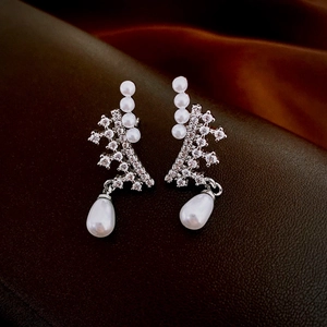 Close-up of silver coral star earrings with teardrop pearls and zircon inlay