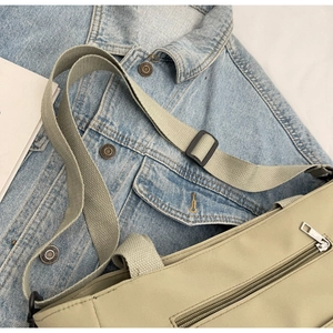 Detail of smooth zipper closure and adjustable wide strap on the beige canvas tote bag
