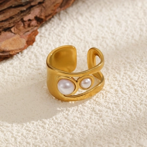 Detail of gold-plated cutout ring with two white pearls on natural wood texture