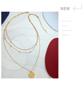 Detailed close-up of layered gold chain necklace featuring a Good Luck engraved round pendant