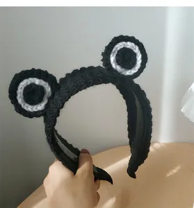 Detail of hand-knitted black headband with 3D cartoon frog eyes and anti-slip inner teeth