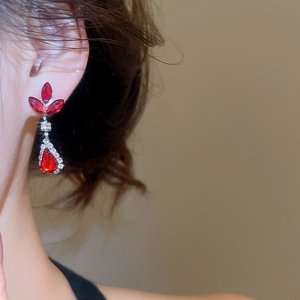 Close-up of elegant red teardrop rhinestone earrings featuring ornate floral leaf design
