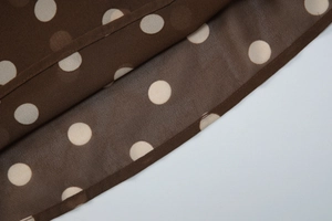 Détail du tissu en mousseline marron à pois blancs avec des coutures d'ourlet délicates