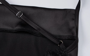 Nahaufnahme eines schwarzen Satin-Kleides mit Spitzenbesatz und silberner Metallschnalle