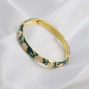 Detail showing dark green enamel bangle with pink floral pattern on white silk
