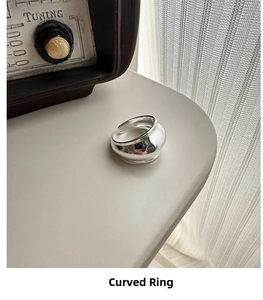 Minimalist S925 sterling silver curved ring styled on a cream surface with vintage radio