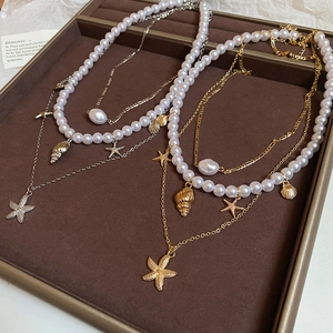 Detail of layered starfish and shell necklaces in gold and silver on a jewelry tray