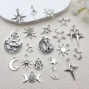Detail of silver alloy star moon and sun pendants with wolf and crow motifs on a white prop