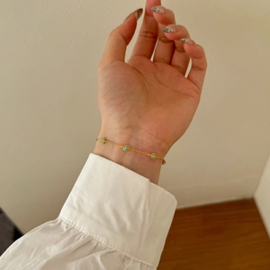 Close-up of elegant gold chain bracelet with blue-green stones on a female wrist