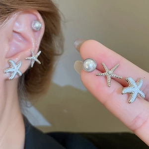 Detailed view of starfish and pearl earrings set with silver needles and enamel finish