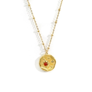 Dettaglio della collana in oro 14k con pietra rossa e incisione a raggiera sul ciondolo