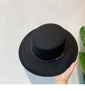 Detail of black wool felt flat top hat featuring a brown leather buckle band accessory