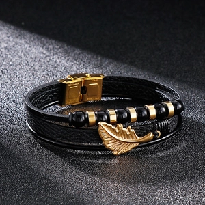 Close-up of men's multi-layer leather bracelet with gold feather pendant and steel clasp