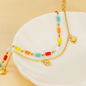 Detail of gold double-layer anklet with colorful rectangular beads and heart charms