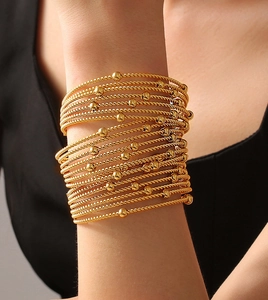 Detail of layered gold bangles featuring twisted rope texture and polished beads