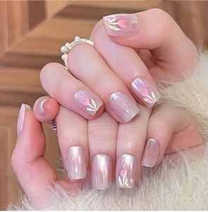 Détail de faux ongles tulipe rose avec effet œil de chat et finition perlée sur main
