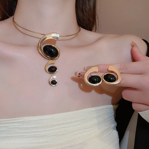 Macro shot of elegant gold oval necklace and earring set with black resin inlay on model