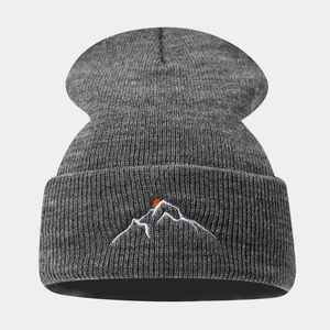 Détail de la broderie montagne et soleil rouge sur un bonnet en maille gris foncé