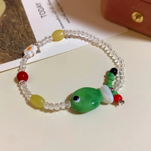 Detail of beaded bracelet with faceted beads and green ceramic fish charm