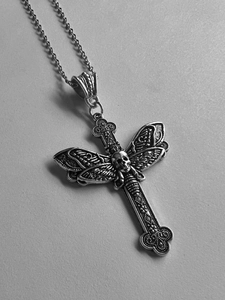 Detailed close-up of a silver gothic cross pendant with skull and wing motifs