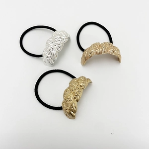 Three elastic hair ties with textured gold and silver metal accents on a clean background