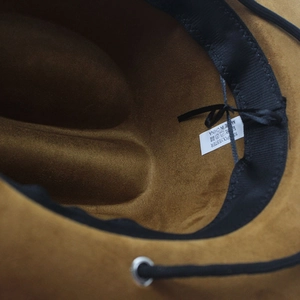 Detail view of the brown faux suede cowboy hat interior with adjustable strap and label