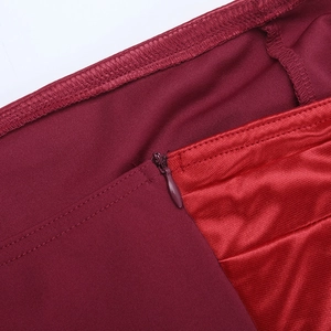 Détail de la fermeture éclair invisible et du tissu en satin lisse sur la robe rouge vin