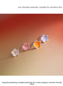 Macro detail of colorful enamel flower earrings featuring hypoallergenic 925 silver needles