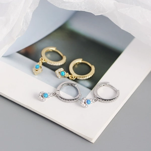 Dettaglio di orecchini a cuore in argento e oro con opale blu e cristalli scintillanti