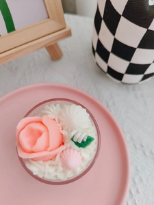 Top view of handmade pink rose candle with white cream frosting and green leaf detail