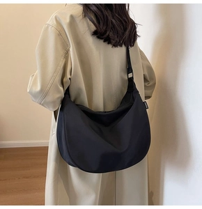 Rear view of model wearing a large black waterproof Oxford crossbody hobo bag