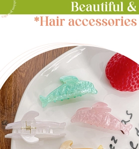 Close-up of glittery candy-colored dolphin hair clips in four pastel shades in a ceramic dish